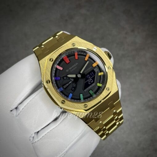 Gold stainless steel Casioak watch featuring a striking black dial and unique rainbow hour markers.