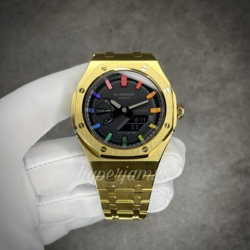 Premium gold stainless steel watch with a full black dial accented by a signature rainbow finish on the hour markers.