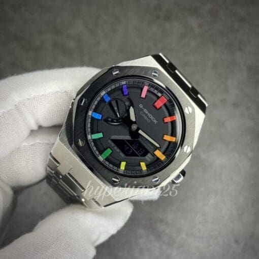 G-Shock 2100 series modification with a distinctive rainbow hour marker design, a black bezel, and a solid stainless steel band.